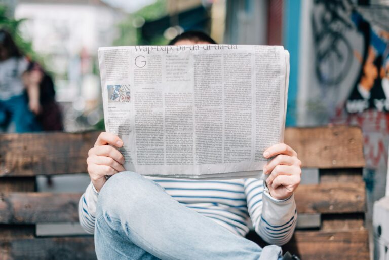 Man reading a newspaper on a bench
